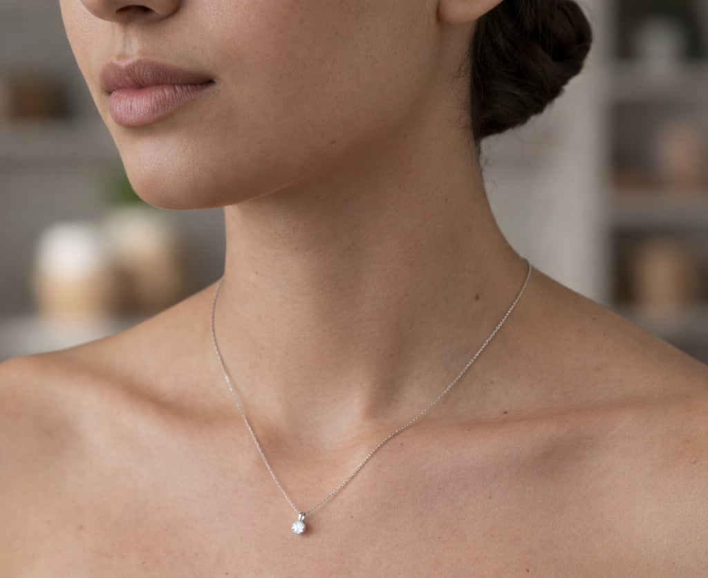 Close-up of a person wearing a delicate silver necklace with a small pendant.